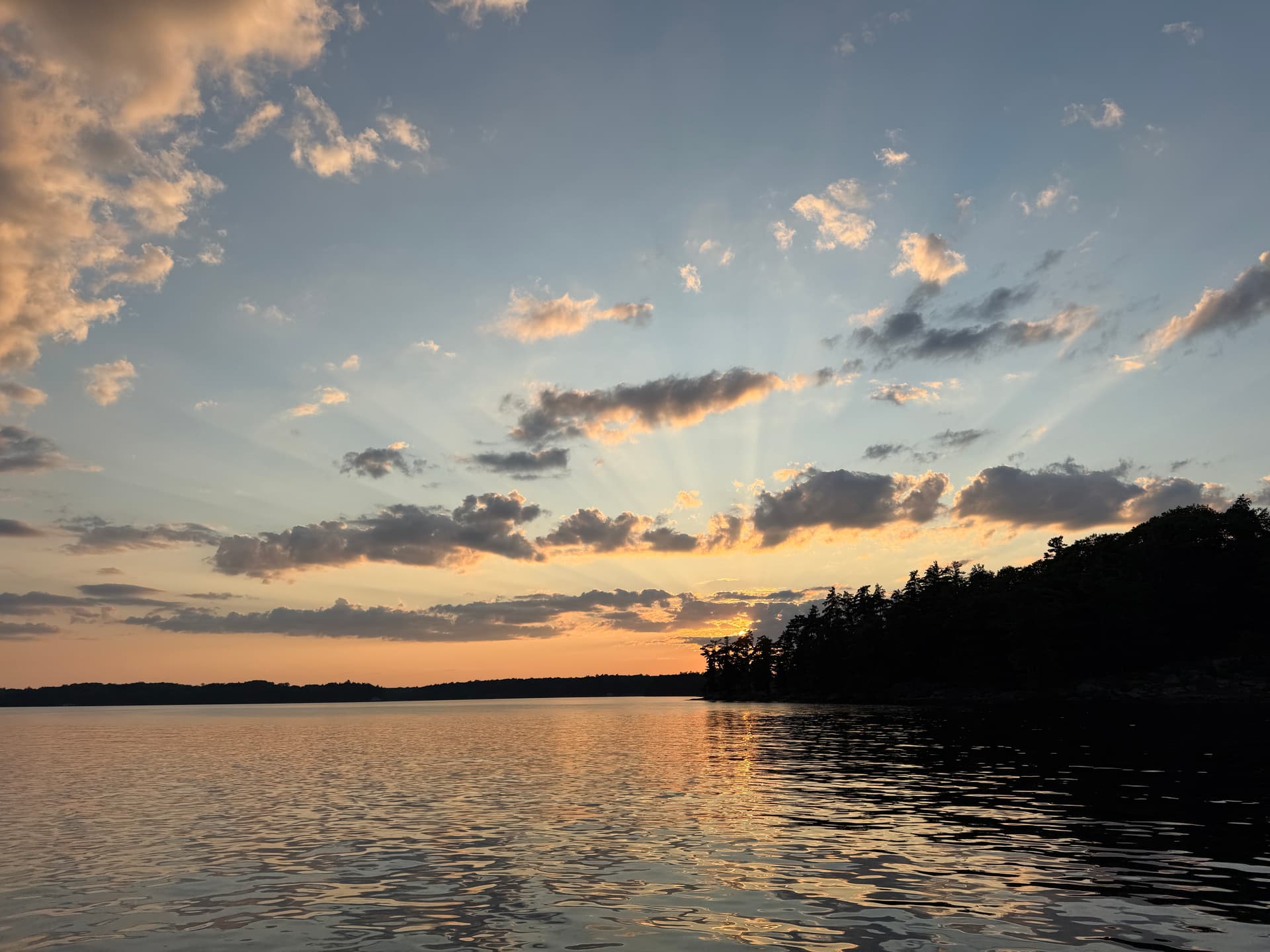 Boat on glass-calm Muskoka lake at golden hour
